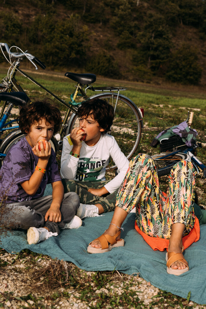 Niños comiendo manzana, tumbados en el césped. 