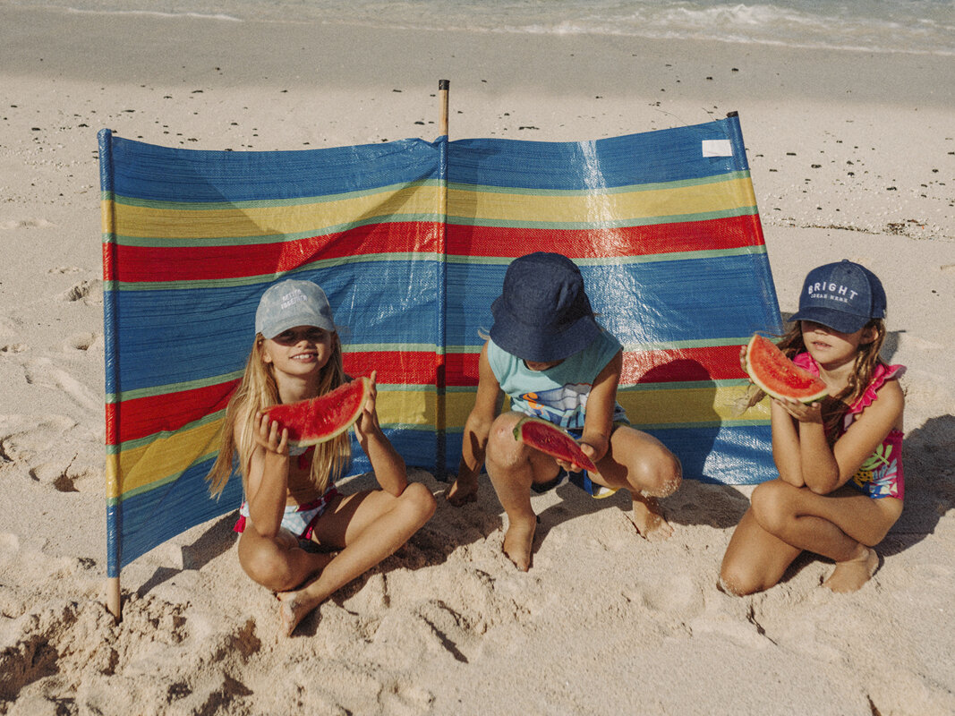 Niños comiendo sandia en la playa